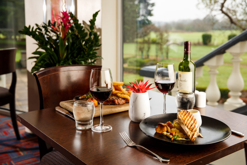 mercure-chester-abbots-well-hotel-restaurant-food-08-lr-190117 Restaurant table, steak and chips, chicken breast, red wine, blurred view of garden out of the window