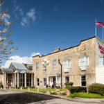 Exterior shot of Mercure York Fairfield Manor Hotel, purple Mercure flags flying