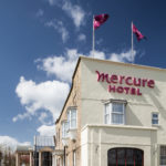 Exterior shot of Mercure York Fairfield Manor Hotel, purple Mercure flags flying