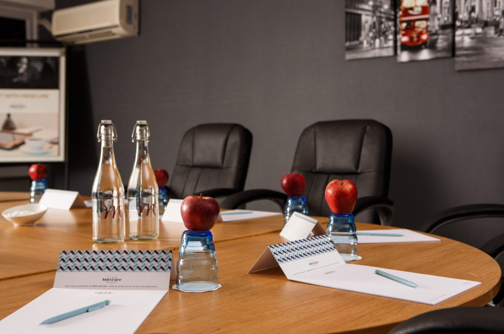 mercure-london-watford-hotel-park-avenue-meeting-detail-01-lr-040315 Meeting table at Mercure London Watford, black leather office chairs around a wooden table with glasses of water and apples
